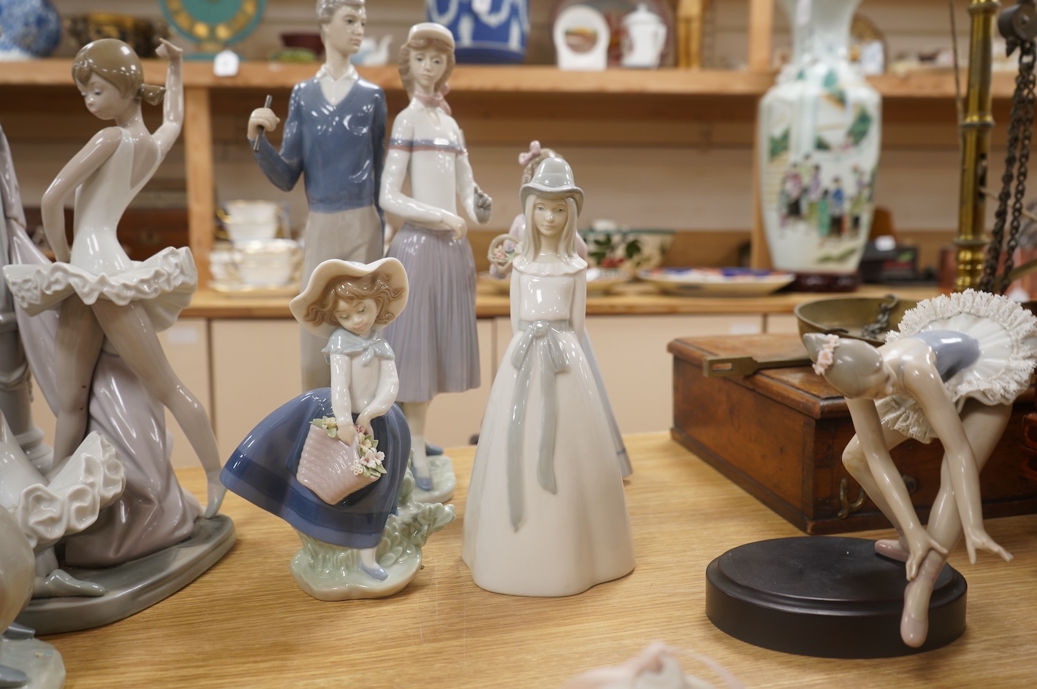 A large Lladro figure group of three ballet dancers by a tall floral column and eight other Lladro figures including a model of a bell. Tallest figure group 45cm high. Condition - golfer group, golf clubs broken.